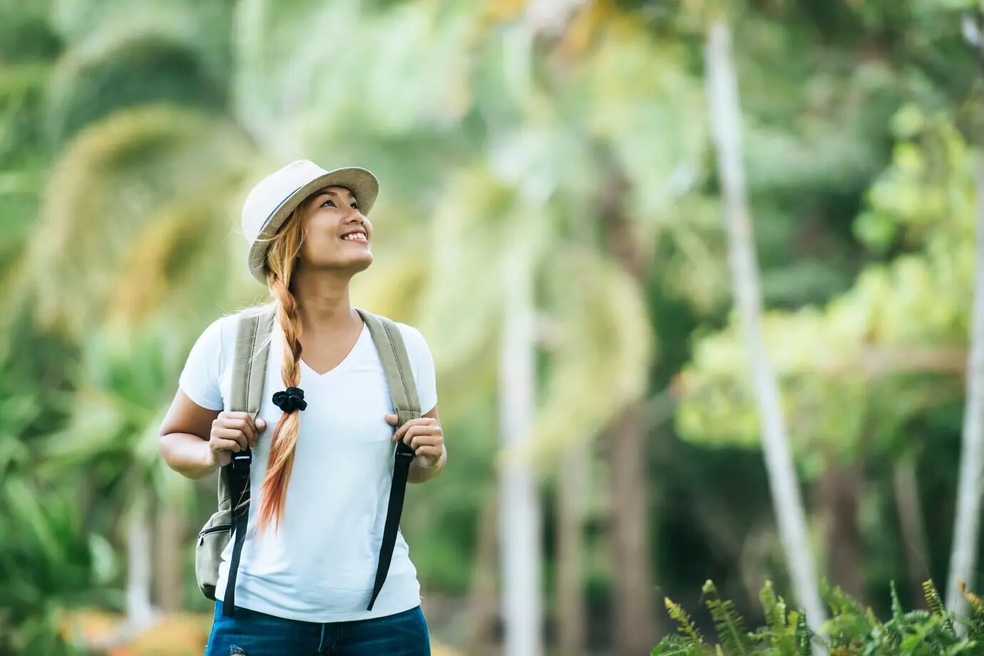 A young woman tourist with a backpack enjoys nature, looking away.